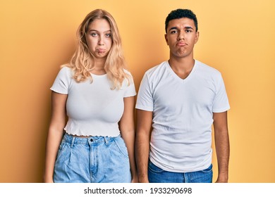 Young Interracial Couple Wearing Casual White Tshirt Depressed And Worry For Distress, Crying Angry And Afraid. Sad Expression. 