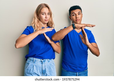 Young Interracial Couple Wearing Casual Clothes Doing Time Out Gesture With Hands, Frustrated And Serious Face 