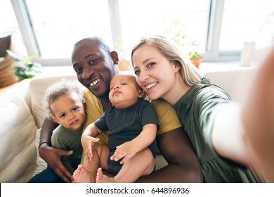 Young interracial family with little children taking selfie.