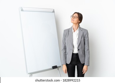 Young Ireland woman isolated on white background giving a presentation on white board and looking up while smiling - Shutterstock ID 1828992215