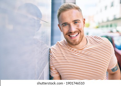Young Irish Man Smiling Happy Leaning On The Wall At Street Of City.