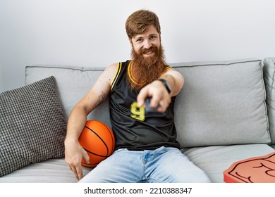 Young Irish Man Smiling Happy Watching Basketball Game On Tv At Home.