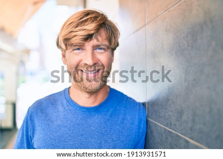 Young irish man smiling happy leaning on the wall at street of city.