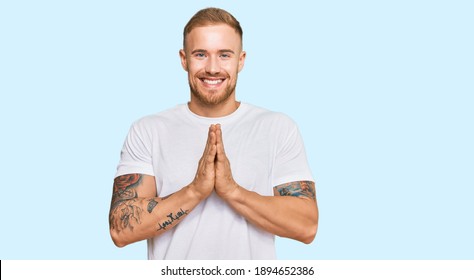 Young irish man wearing casual clothes praying with hands together asking for forgiveness smiling confident. 