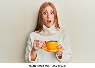 Young irish woman drinking a cup of coffee afraid and shocked with surprise and amazed expression, fear and excited face. 