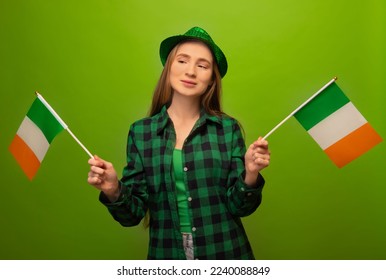 Young irish woman in green checkered plaid shirt with hat holding two small national flags of Ireland and looking aside isolated on green background.

St Patricks Day celebration concept. - Powered by Shutterstock