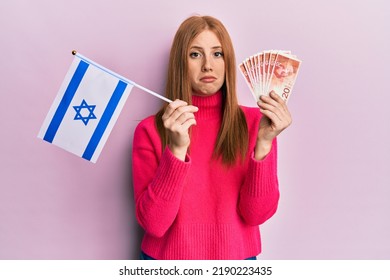 Young Irish Woman Holding Israel Flag And Shekels Banknotes Depressed And Worry For Distress, Crying Angry And Afraid. Sad Expression. 