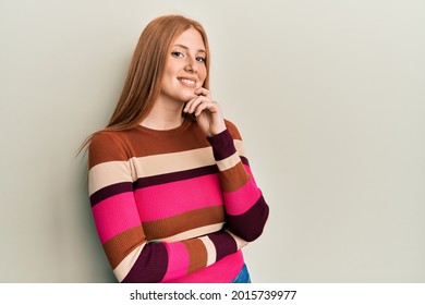 Young irish woman wearing casual clothes looking confident at the camera with smile with crossed arms and hand raised on chin. thinking positive. 