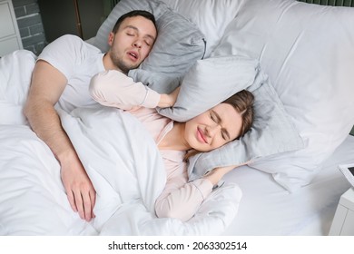 Young Irritated Woman In Bed With Snoring Husband