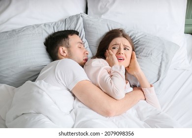 Young Irritated Woman In Bed With Snoring Husband