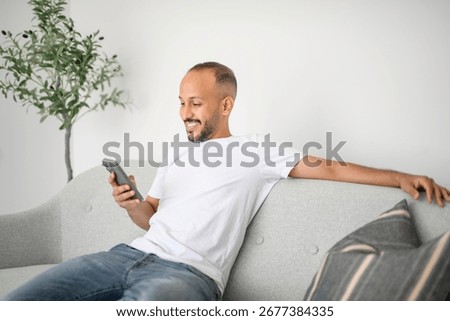 A young islamic arab man using cellphone on sofa at home