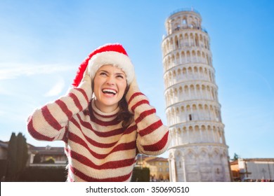Young, itching from energy and searching for excitement. I'm going to Christmas trip to Italy. It is a no-brainer. Happy woman in Santa hat looking up on something in front of Leaning Tour of Pisa.