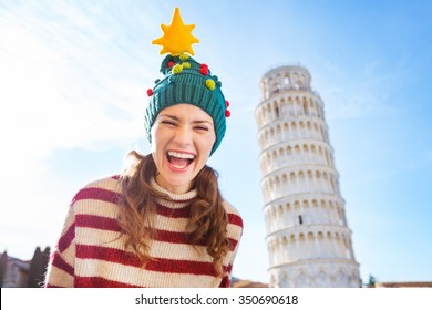 Young, itching from energy and searching for excitement. I'm going to Christmas trip to Italy. It is a no-brainer. Portrait of happy woman in Christmas tree hat in front of Leaning Tour of Pisa