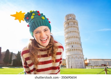 Young, itching from energy and searching for excitement. I'm going to Christmas trip to Italy. It is a no-brainer. Portrait of merry young woman in Christmas tree hat in front of Leaning Tour of Pisa