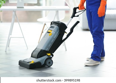 Young Janitor With Washing Machine Cleaning Floor In Office