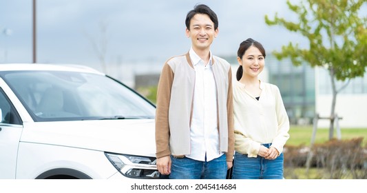 Young Japanese Couple Rejoicing In Front Of The Car