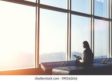 Young Japanese Female Is Sitting In Modern Airport Interior And Connecting To Free Wireless For Make Hotel Booking In City Of Arrival. Attractive Chinese Is Using Digital Tablet And Waiting Her Fly 