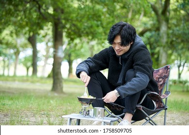 A Young Japanese Man Cooking Alone In A Camp