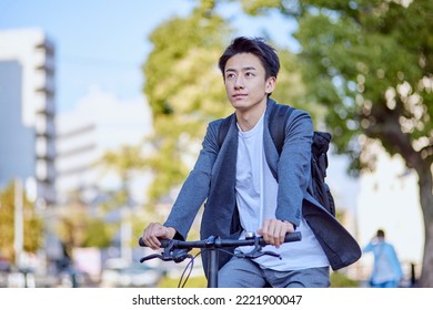 Young Japanese man in a jacket riding a bicycle