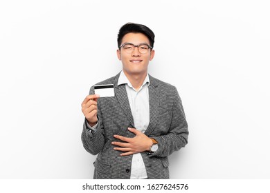 Young Japanese Man Laughing Out Loud At Some Hilarious Joke, Feeling Happy And Cheerful, Having Fun. Credit Card Concept.