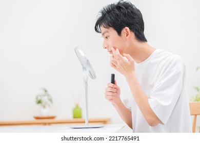 Young Japanese Man Looking In The Mirror And Applying Makeup