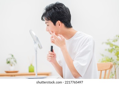 Young Japanese Man Looking In The Mirror And Applying Makeup