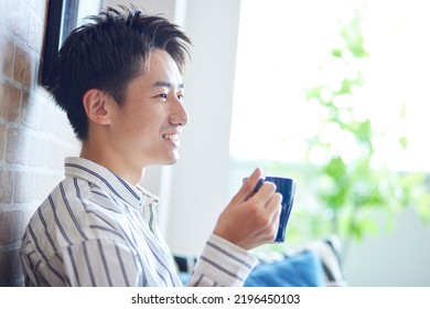 Young Japanese Man Relaxing In The Living Room