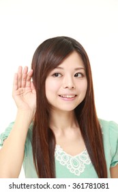 Young Japanese Woman With Hand Behind Ear Listening Closely