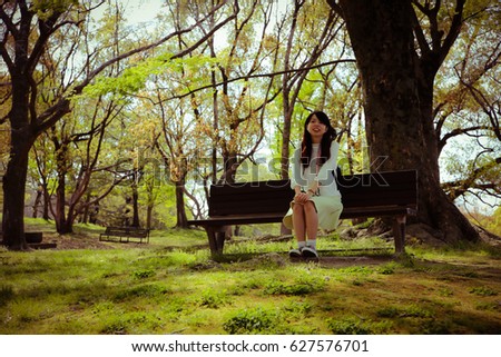 Similar – Junge Frau sitzt auf einer Bank in einem Park in ruhiger Pose.