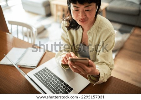Young Japanese woman using a smart phone in the living room