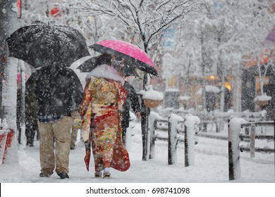 Young Japanese Woman Wearing A Colorful Kimono And Walking Outside In Tokyo During A Snow Storm.