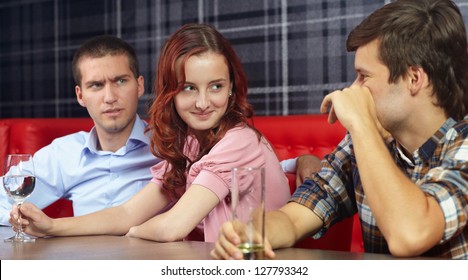 Young jealous angry man looking at his girlfriend sitting in a restaurant
