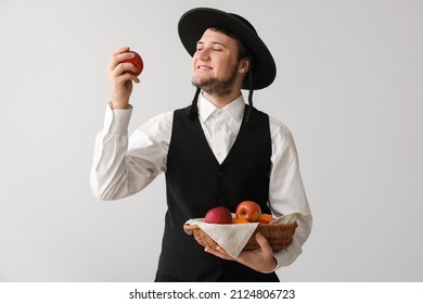 Young Jewish Man With Fruits In Basket On Grey Background