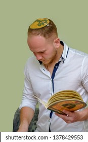 Young Jewish Man With Kippah Reads The Passover Haggadah.