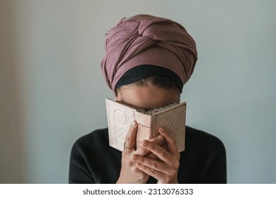 Young jewish woman with a covered head prays with a siddur (jewish prayer book) in her hands, covered his face with her hands (66)