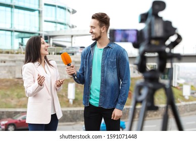 Young journalist interviewing businesswoman on city street