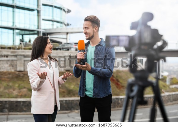 Young journalist interviewing businesswoman on\
city street