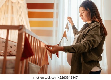 A young joyful pregnant woman is at home decorating the baby nursery. - Powered by Shutterstock