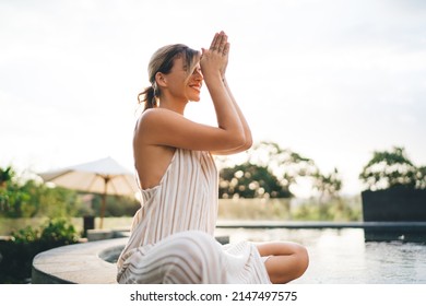 Young joyful woman practicing yoga and meditating on swimming pool edge in yard of resort hotel. Tourism, vacation and weekend. Caucasian girl. Sunset. Idyllic and tranquility lifestyle on Bali island - Shutterstock ID 2147497575