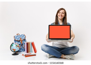Young joyful woman student holding laptop pc computer with blank black empty screen sitting near globe, backpack school books isolated on white background. Education in high school university college
