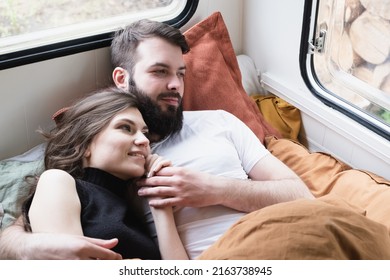 Young Just Married Couple Is Traveling In Travel Van. Romantic Atmosphere Of Relaxation. Road Trip Around Country For Weekend. Caucasian Man And Woman Lying In Bedroom In Camper. Millennial Generation