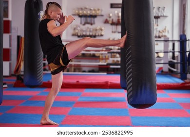 Young kickboxer training on the heavy bag in a kickboxing gym - Powered by Shutterstock