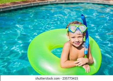 Young Kid Having Fun In The Swimming Pool On Inner Tube Raft. Summer Vacation Fun. 