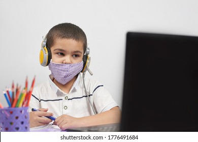 Young kid in headphones doing online exercises via laptop. Learning foreign language online or distance education, e-learning concepts