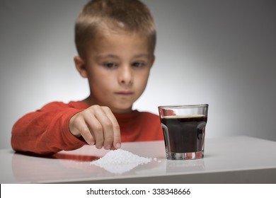 Young Kid Looks In Front Of Sugar Sweetened Soft Drink. The Over-consumption Of Sugar-sweetened Soft Drinks Is Associated With Obesity, Type 2 Diabetes, Dental Caries, And Low Nutrient Levels.