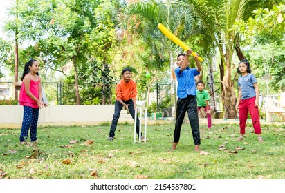 Young Kid Running By Hitting The Ball While Playing Cricket At Park For Scoring - Conept Of Childhood Physical Activities, Vitality And Entertainment