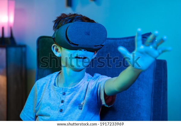 Young kid with\
VR or virtual reality headset feeling or enjoying the 360 degree\
virtual environment - Concept of showing futuristic of modern VR\
technology in modern\
lifestyle