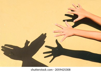 Young Kids Making Different Shadow Symbols With Hands On The Wall