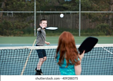 Young Kids Playing Pickleball On An Outdoor Court. 