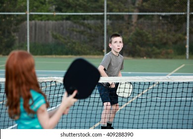 Young Kids Playing Pickleball On An Outdoor Court. 